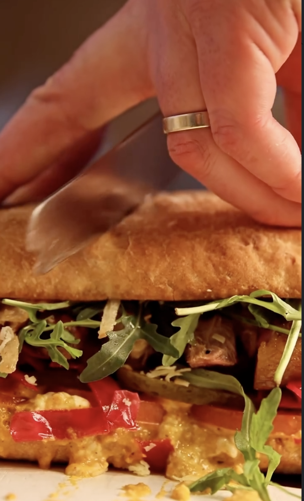 Cutting into a loaded sandwich with The Indoor BBQ sauce